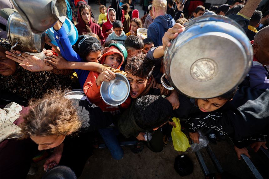 Displaced Palestinians gather to receive food portions at a charity kitchen in the Nuseirat refugee camp in the central Gaza Strip on December 20, 2025.