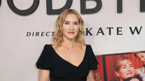 FilmMagic via Getty Images Kate Winslet smiles as she stands in front of a poster of her new film.