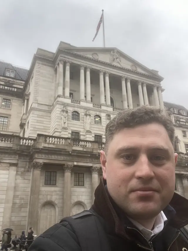 BBC journalist Michael Race wearing a black coat as he stands in front of the Bank of England building