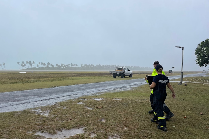 Two emergency service workers survey the rain amid Cyclone Grant.
