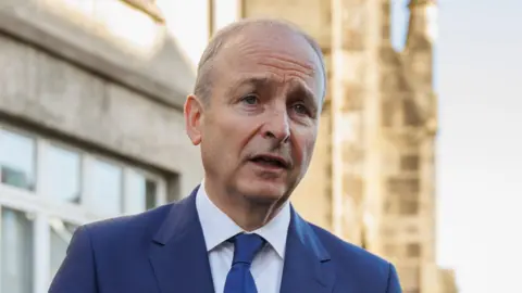 PA Media Michael Martin has short grey hair and is talking to the camera. He is wearing a blue navy suit, white shirt and blue tie.