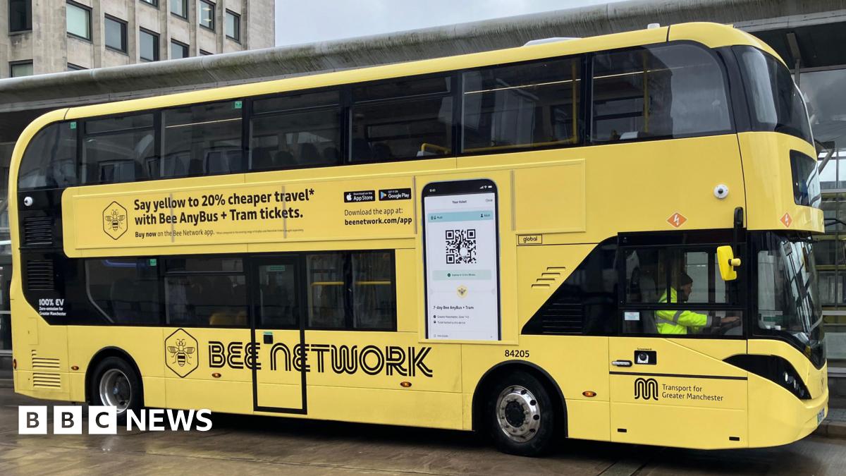 A yellow Bee Network branded double-decker bus in its depot