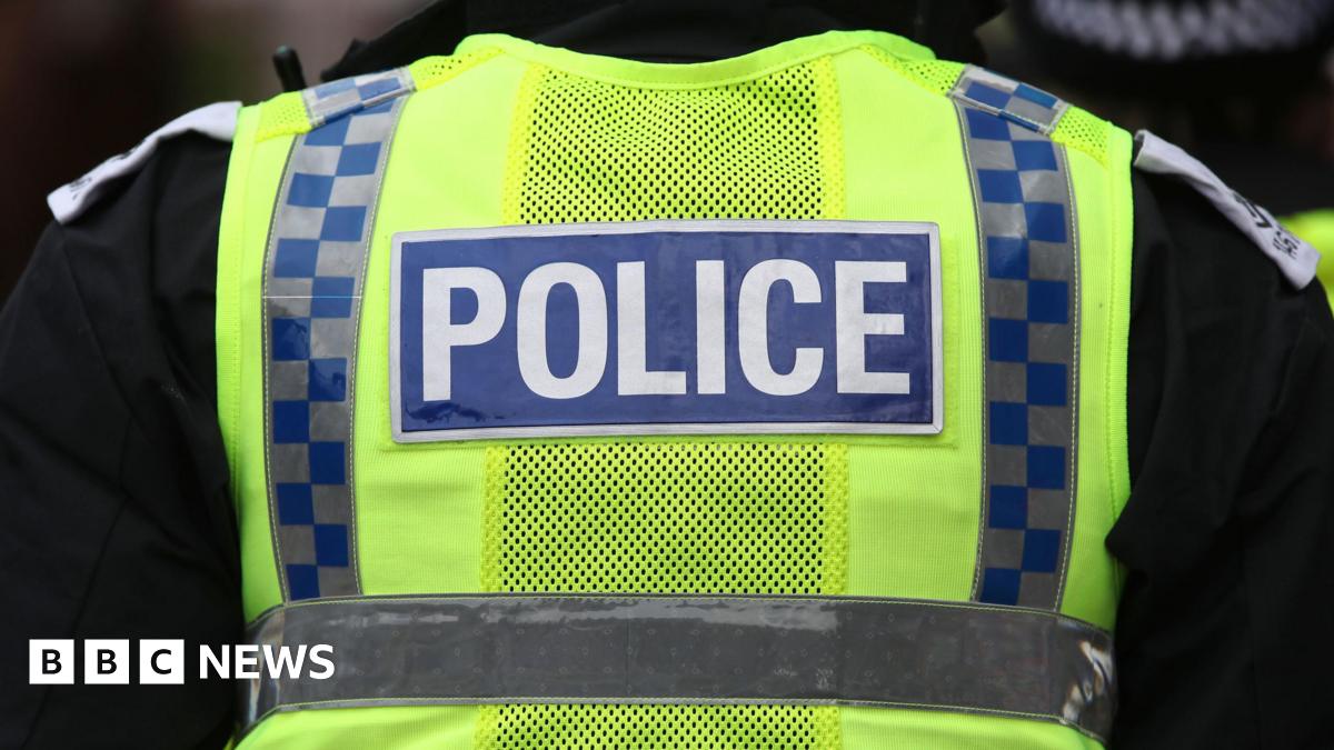 A police officer wearing a hi-viz vest over a black shirt.