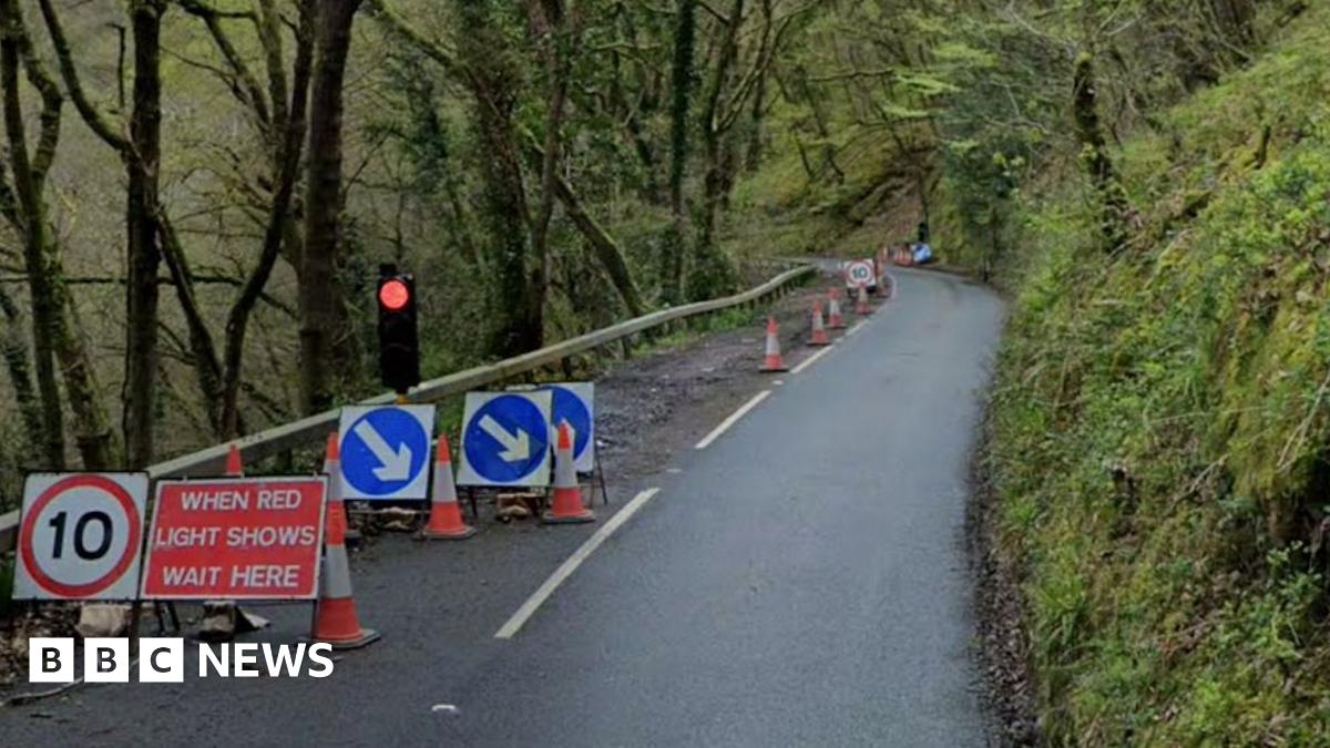 Signage showing a 10mph speed limit and a red traffic light at the start of the lane closure on the B3212 going through woodland between Doccombe and Dunsford