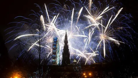 Getty Images White fireworks light up the night sky above the Scott Monument and Ferris wheel in Edinburgh.