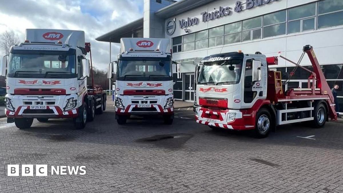 Three large white and red trucks, parked in front of an office building
