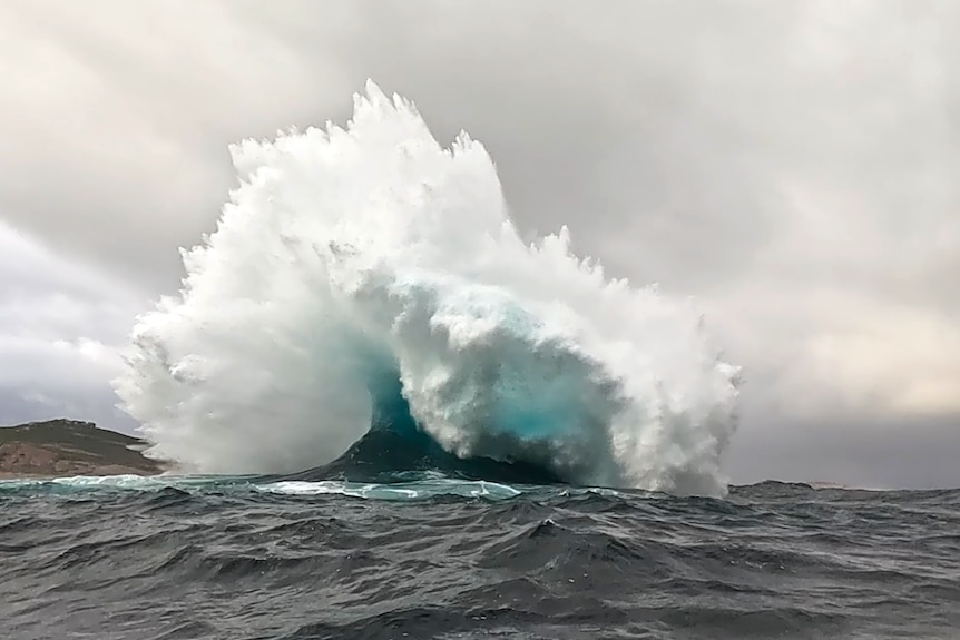 A massive wave bursts into the air.