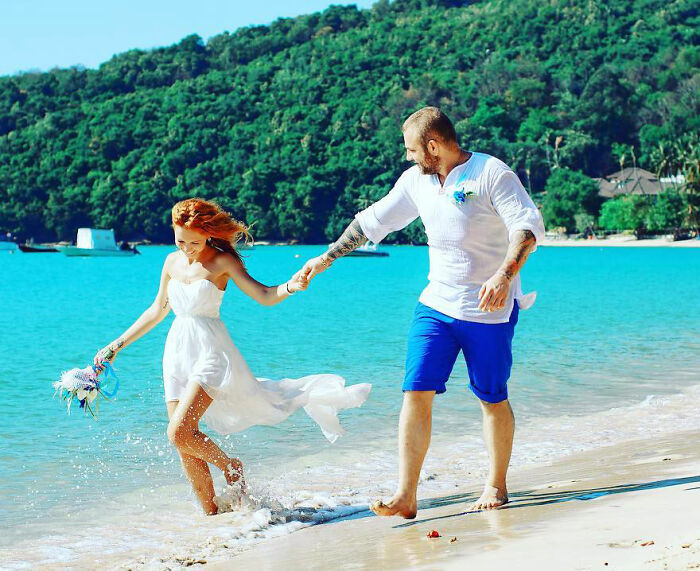 Couple holding hands on a beach with ocean and green hills, unrelated to crypto scammer case in Dubai Mall.