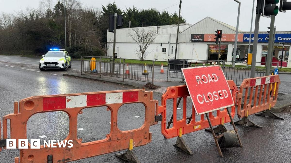 A road closed sign and a police car with a garage in the background