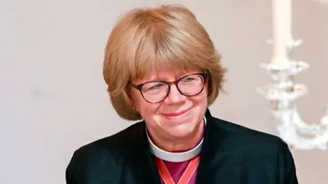 Getty Images Sarah Mullally pictured smiling. She has short blonde hair and is wearing glasses. 