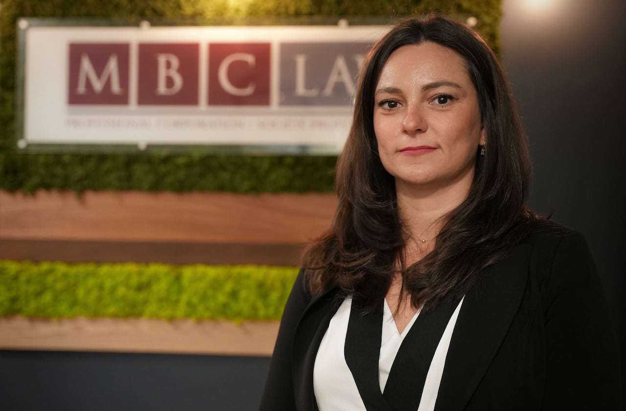 A woman stands in front of a lawfirm sign.