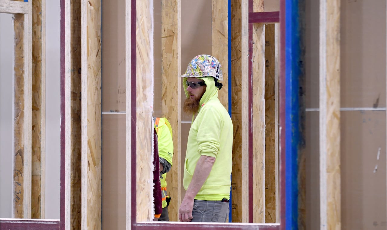 A worker is seen through the wood framing of a partially built home. 