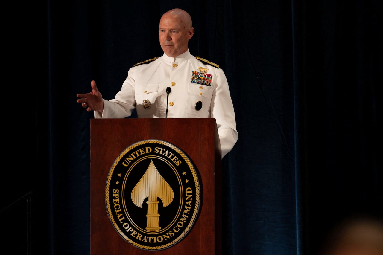 Man in white military uniform speaks at a podium