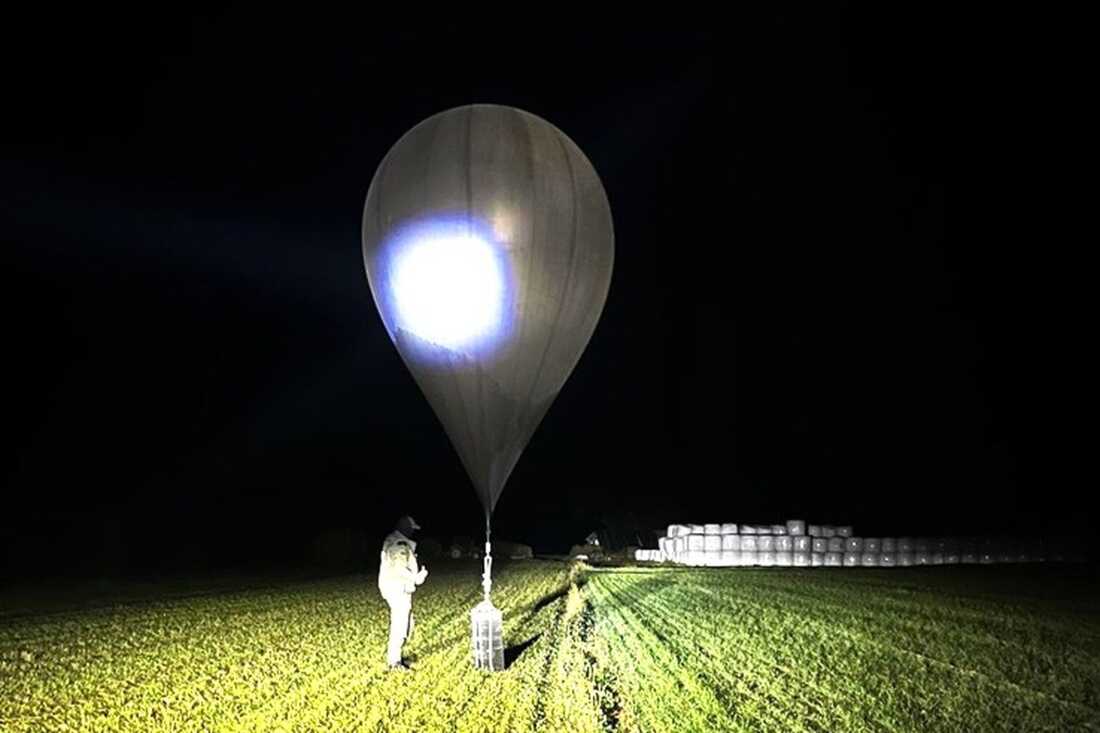 FILE - In this undated photo released by the State Border Guard Service, an officer inspects a balloon used to carry cigarettes into Lithuania, because Belarussian smugglers often use them to ferry the contraband into the European Union