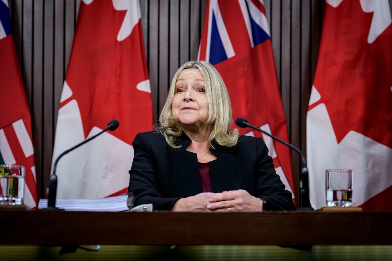 A woman sitting at a desk folds her hands in front of her.