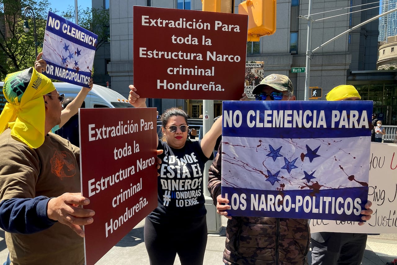Several people, men and women, are shown holding signs in Spanish at an outdoor demonstration. 