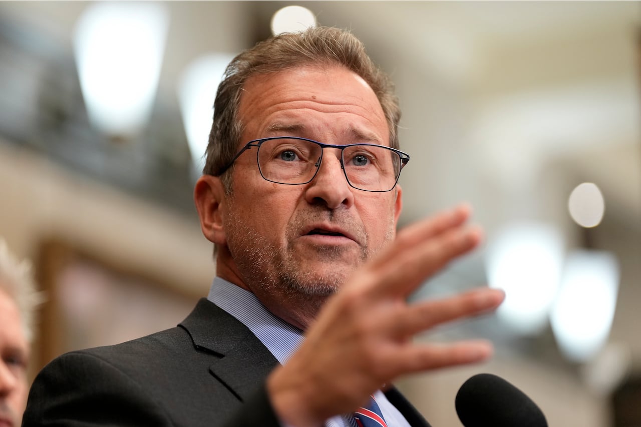 A man stands and gestures at a microphone.