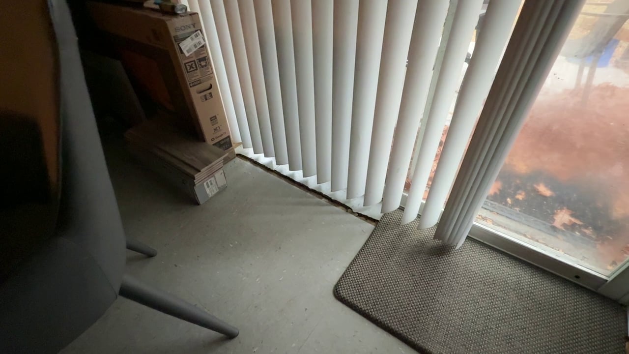 A large crack in a floor next to a patio door.