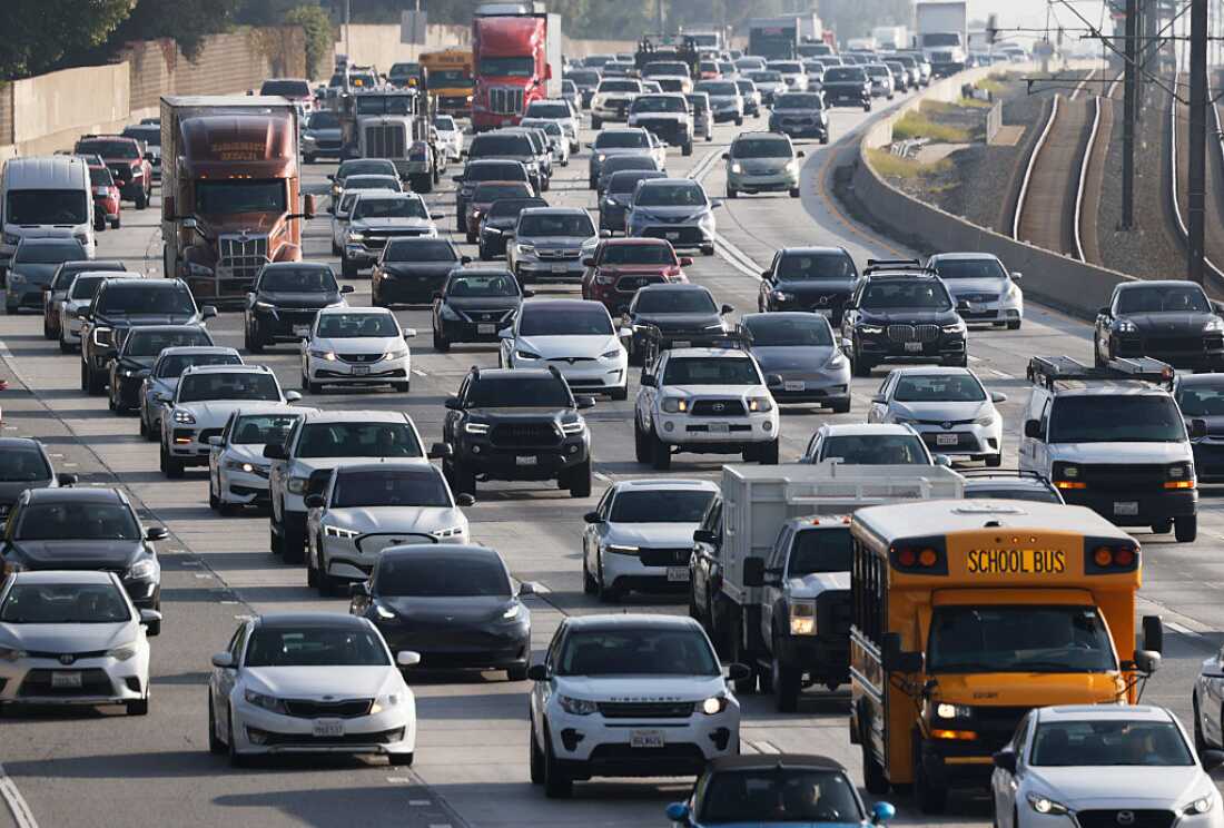 Cars, trucks and school buses fill six lanes of traffic on Interstate 210 during the morning commute in Pasadena, California, in December 2025.
