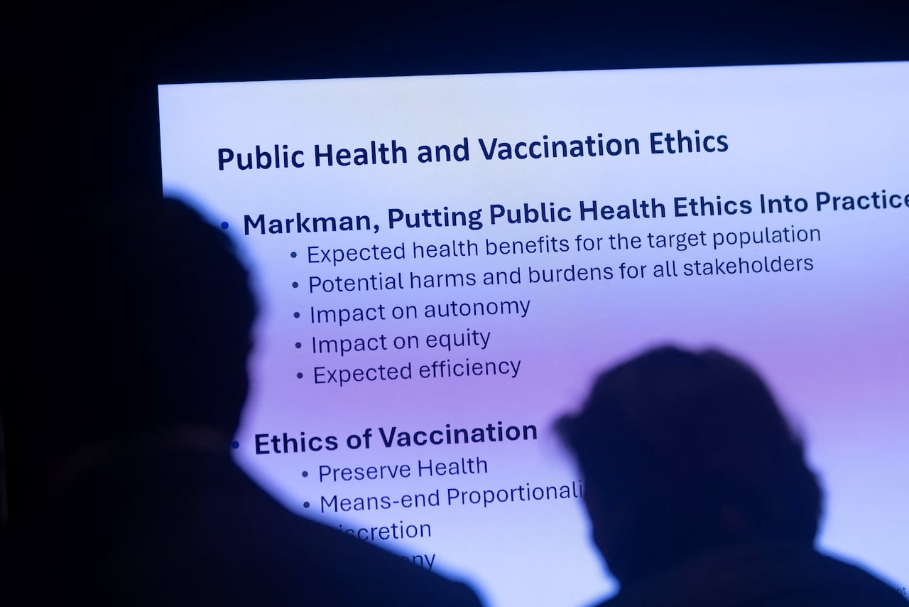 black text on a white screen is visible past heads of attendees who are lookign at the presentation on screen