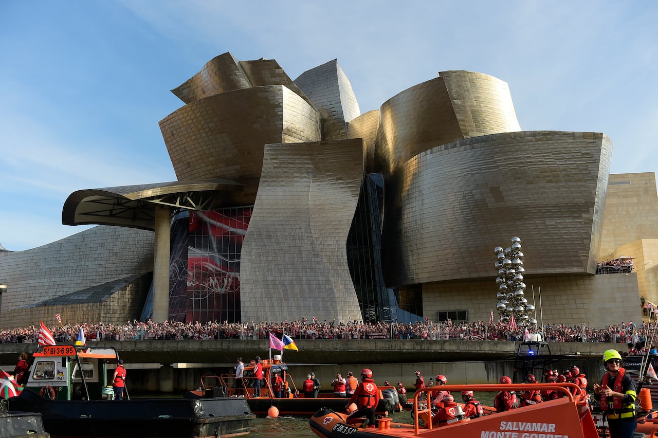 Athletic Bilbao fans wait in front of the Guggenheim museum as support boats pass before team celebrations on the Nervion Estuary in Bilbao, Spain, Thursday, April 11, 2024. (AP Photo/Alvaro Barrientos)