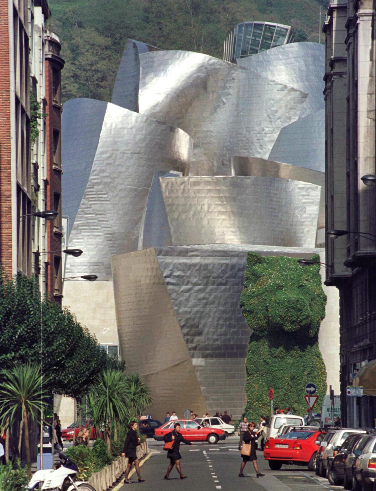 The curving, shimmering forms of the Guggenheim Bilbao as seen through a narrow lane