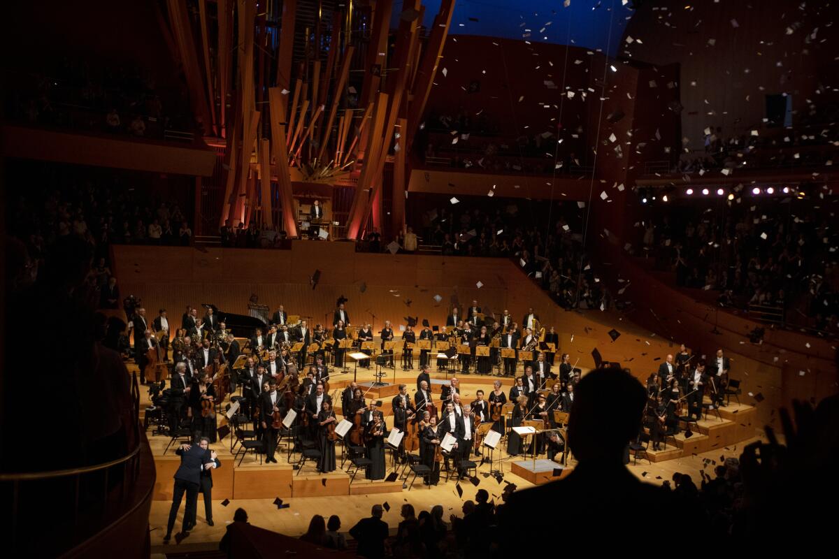 Confetti rains down on the orchestra standing on the wooden stage inside Disney Hall.