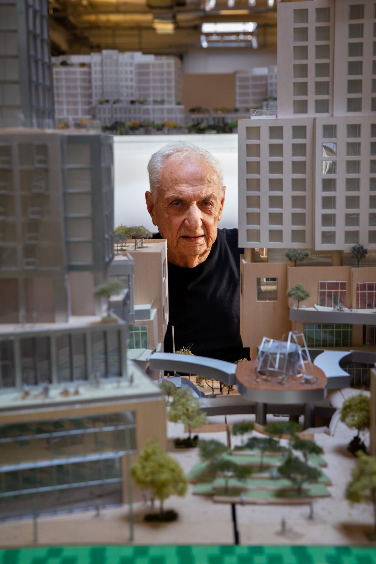 Frank Gehry peers through an architectural model.