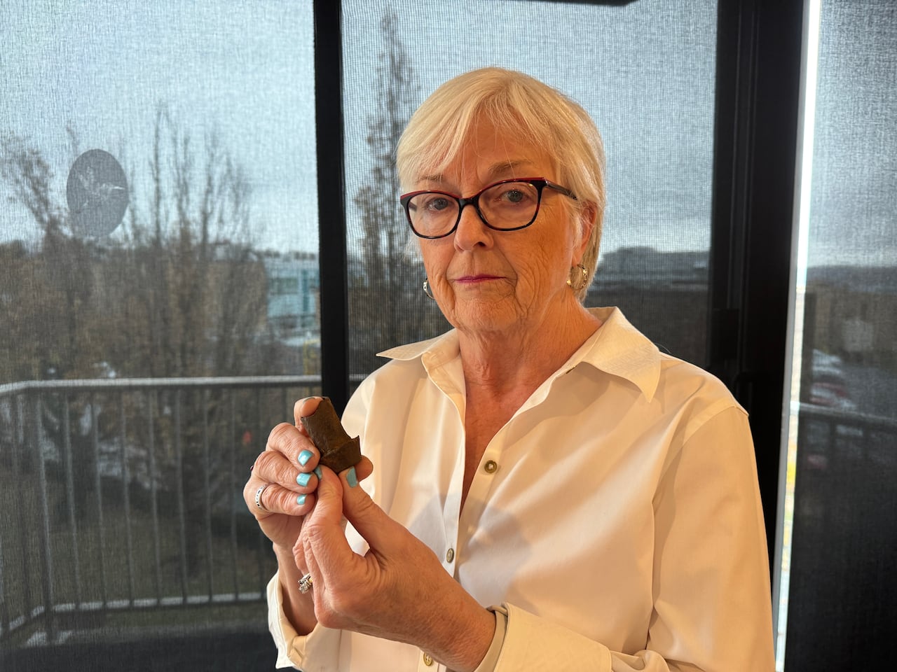 A woman holds a rusty rivet from a ship involved in the Halifax Explosion.