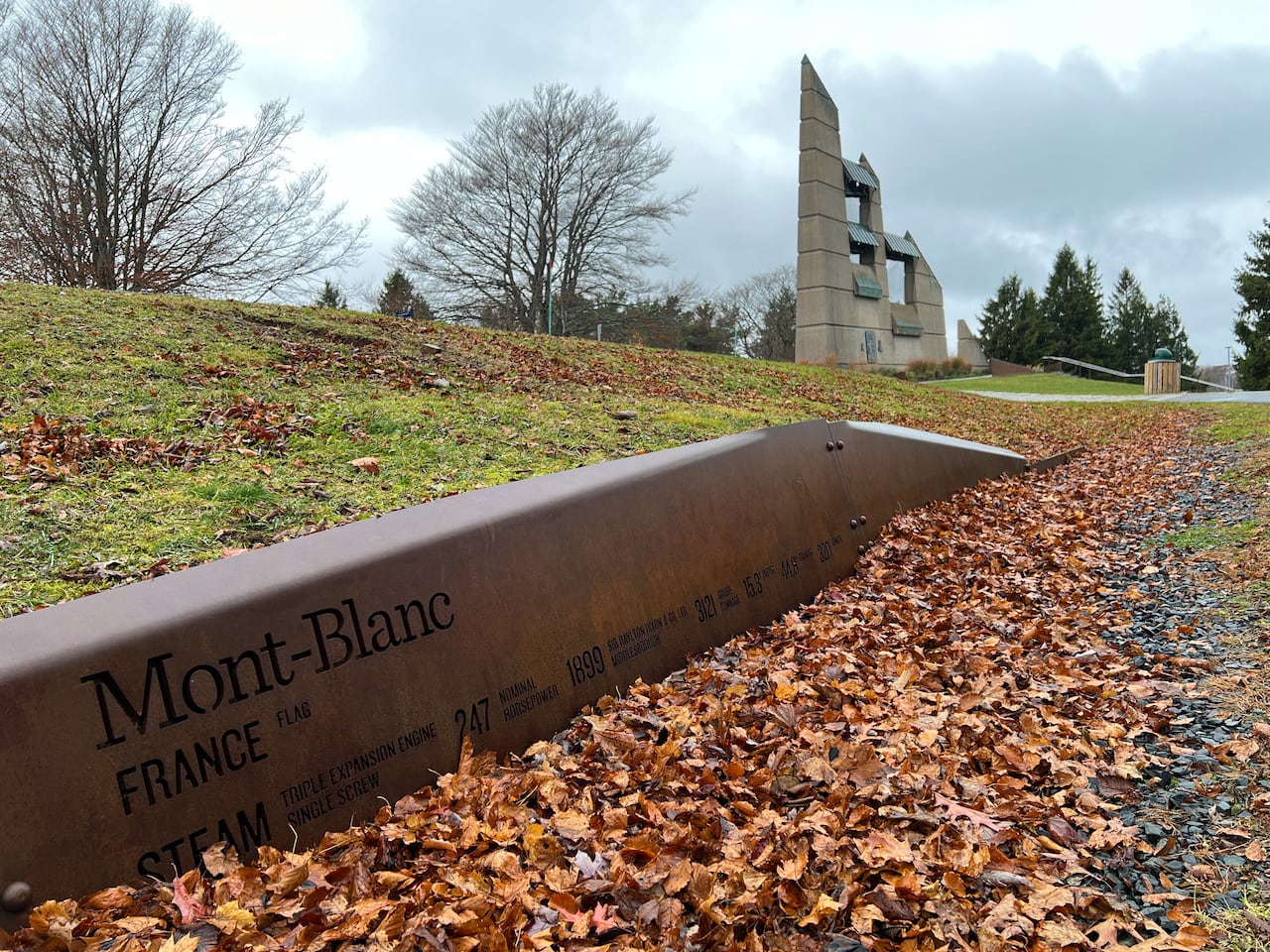 A monument honouring victims of the Halifax Explosion is shown on a fall day with leaves on the ground.
