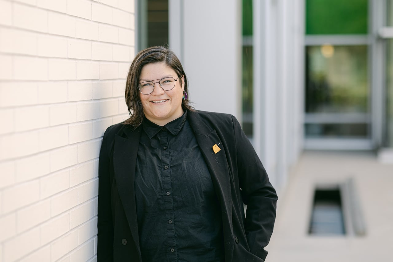 A woman stands next to a wall.