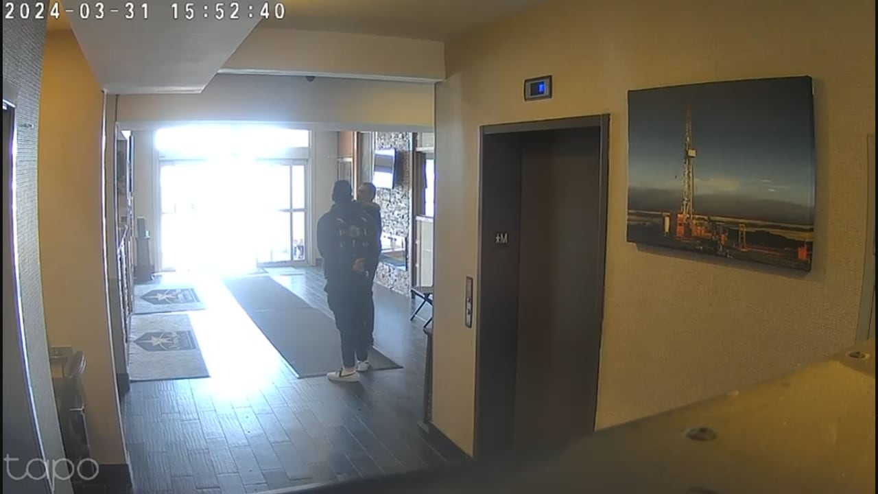 A still image showing two people in a lobby.