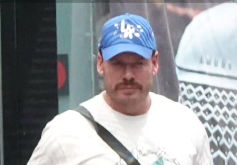 A man wearing a ball cap, t-shirt and jeans, with his hands in his pockets