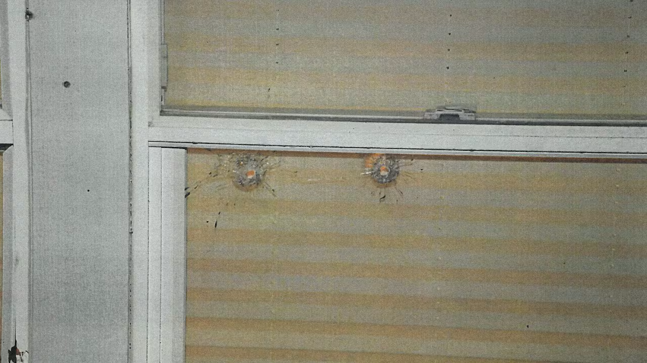 Bullet holes are seen in a window.