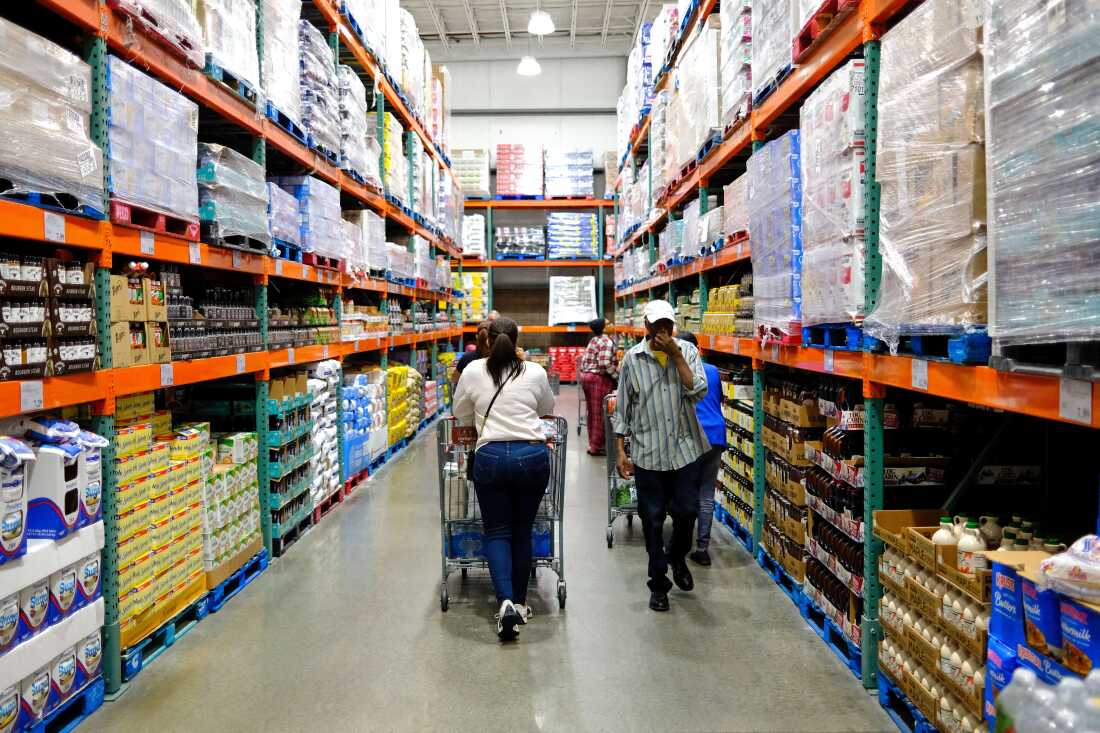 Customers push shopping carts down an aisle of a large, warehouse-like discount supermarket in Union, New Jersey, on September 22. Large quantities of groceries are stacked on pallets that are on shelves that nearly reach the ceiling.
