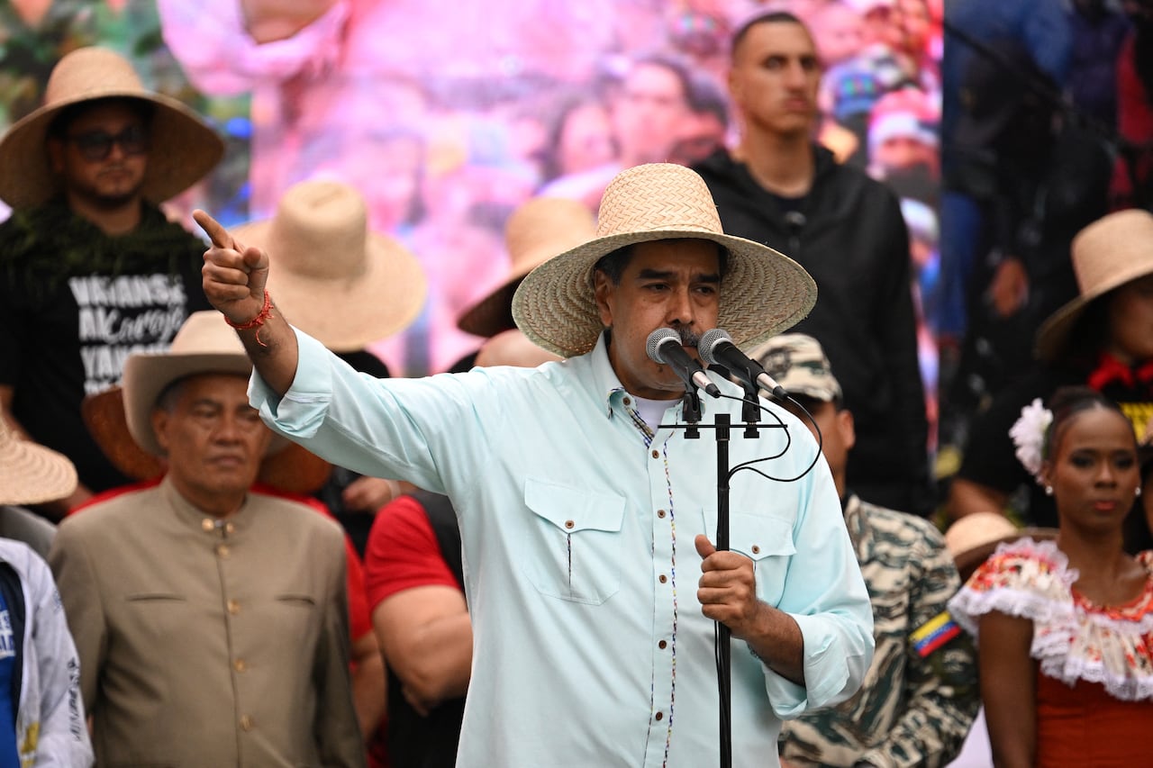 Venezuelan President Nicolás Maduro standing in front of a microphone, while pointing