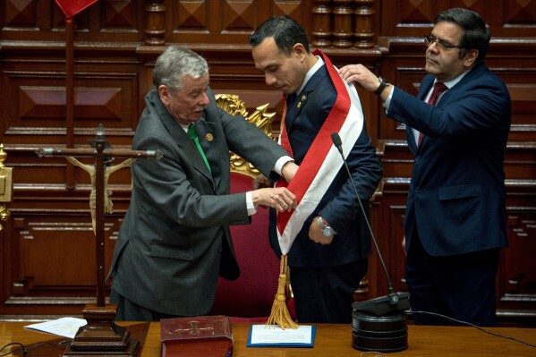 Peru's former president of the Congress Jose Jeri, center, receives the presidential sash from congressman Fernando Rospigliosi, left, as he is sworn-in as the interim president in Lima, Peru, Friday, Oct. 10, 2025. (AP Photo/John Reyes)