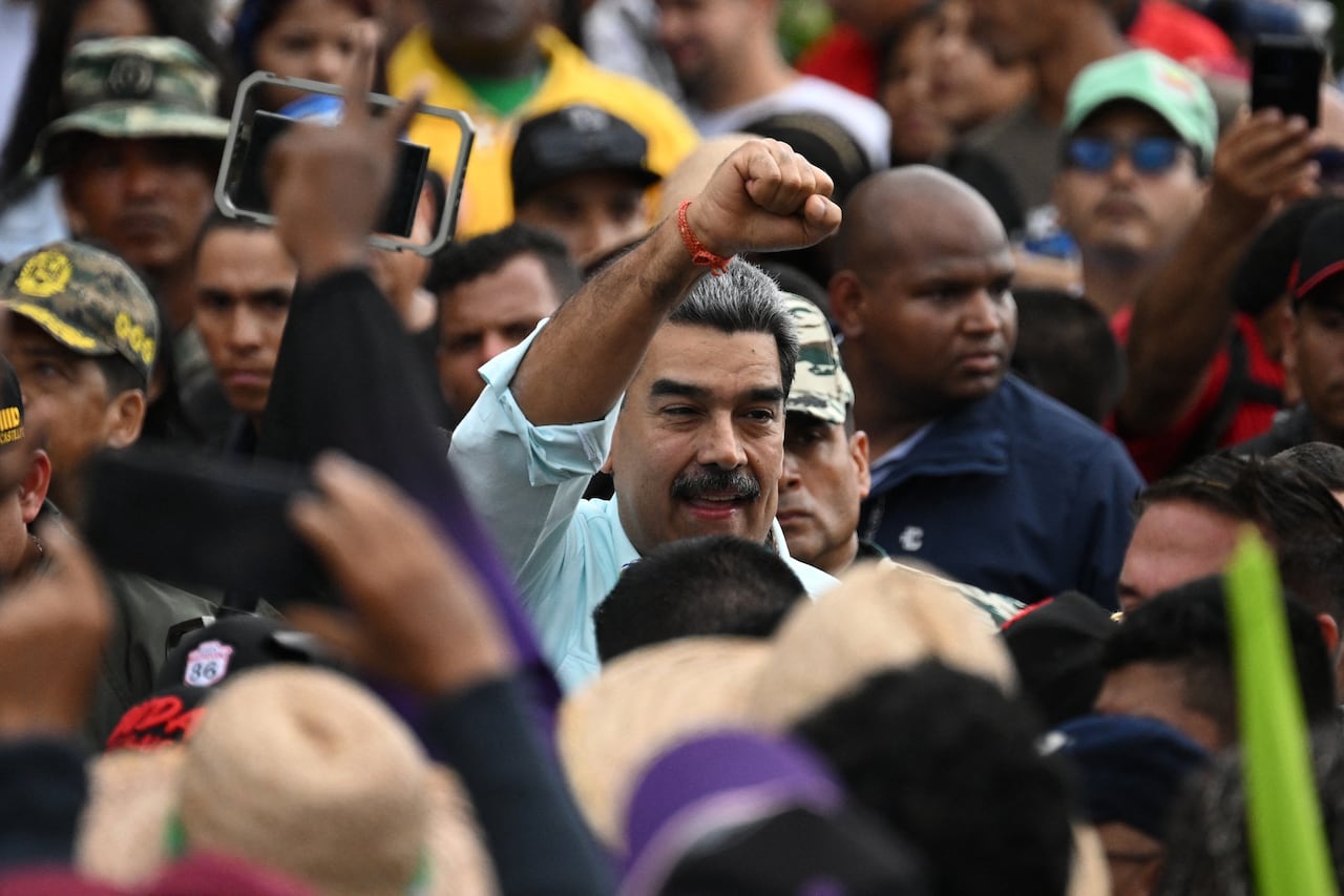 A man makes a fist and holds it aloft, amid a crowd of people