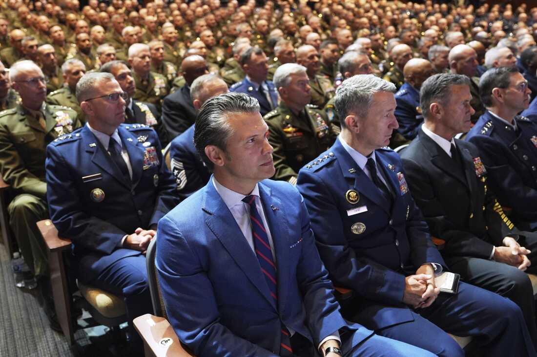 Defense Secretary Pete Hegseth, center, sitting with other senior military leaders, listen as President Trump speaks at Marine Corps Base Quantico in September 2025.
