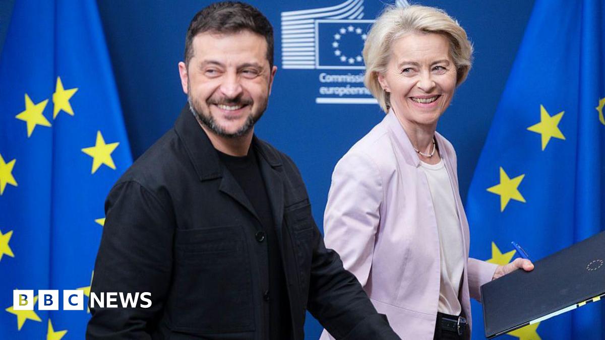 President of Ukraine Volodymyr Zelenskyy (L) and the EU Commission President Ursula von der Leyen (R) walk in front of blue and yellow-starred European Union flags