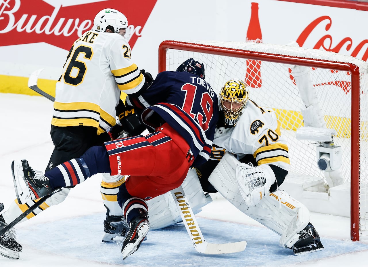 Three hockey players get tight near the crease area.