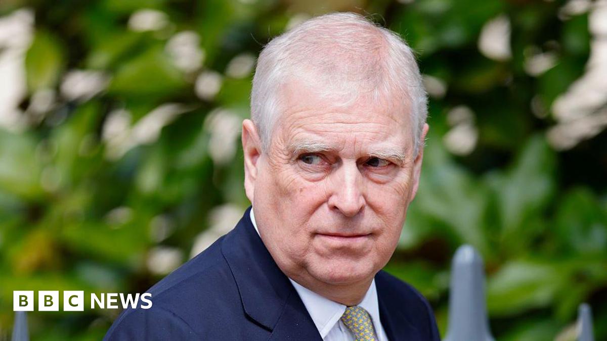 Andrew Mountbatten-Windsor wearing a navy suit looks to one side