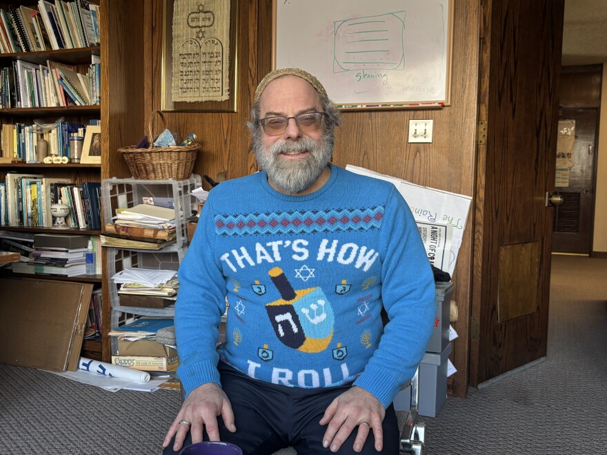 Rabbi Daniel Swartz sits in his office at Temple Hesed in Scranton with a Hanukkah sweater that depicts a dreidel and says, 'That's how I roll.' A dreidel is a four-sided top inscribed with Hebrew letters, and traditionally used during Hanukkah.