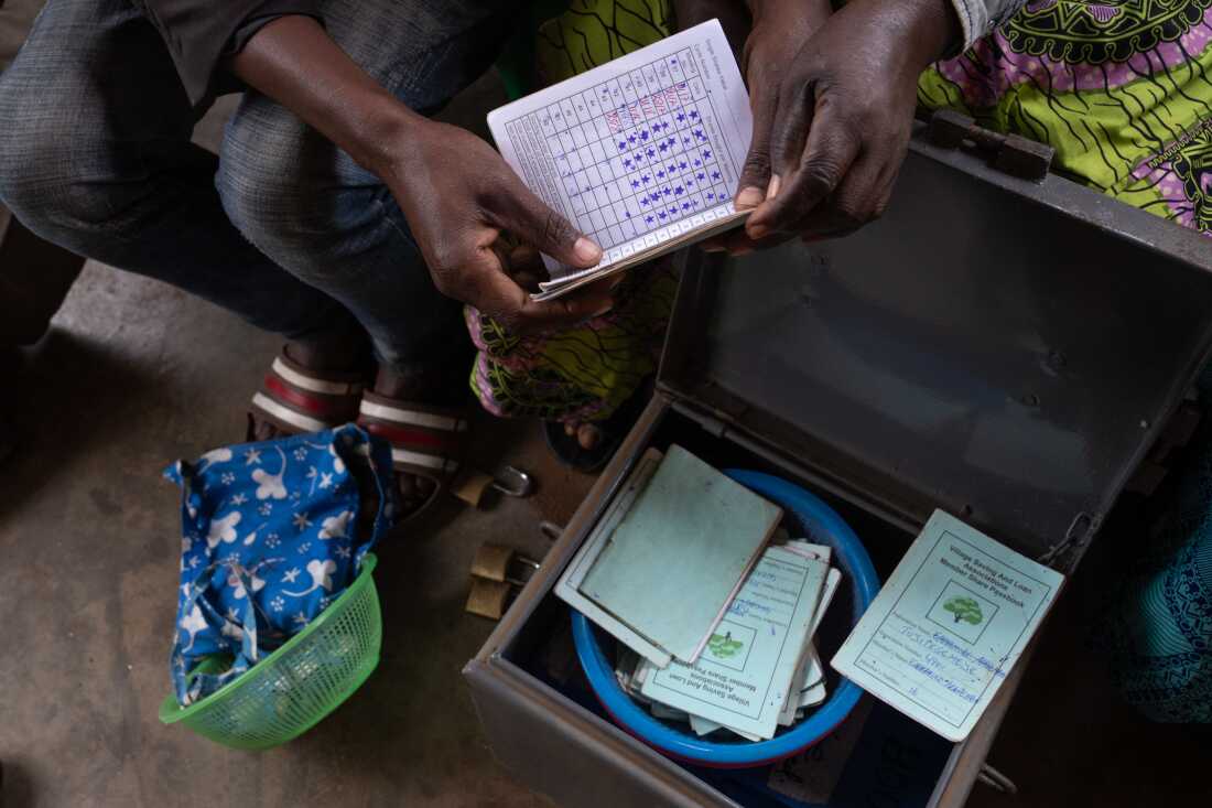 Members of Tujitegemeye group show some of their records that are kept in a locked box for AVSI's Smiles Project in Kyaka 2 Refugee Settlement.