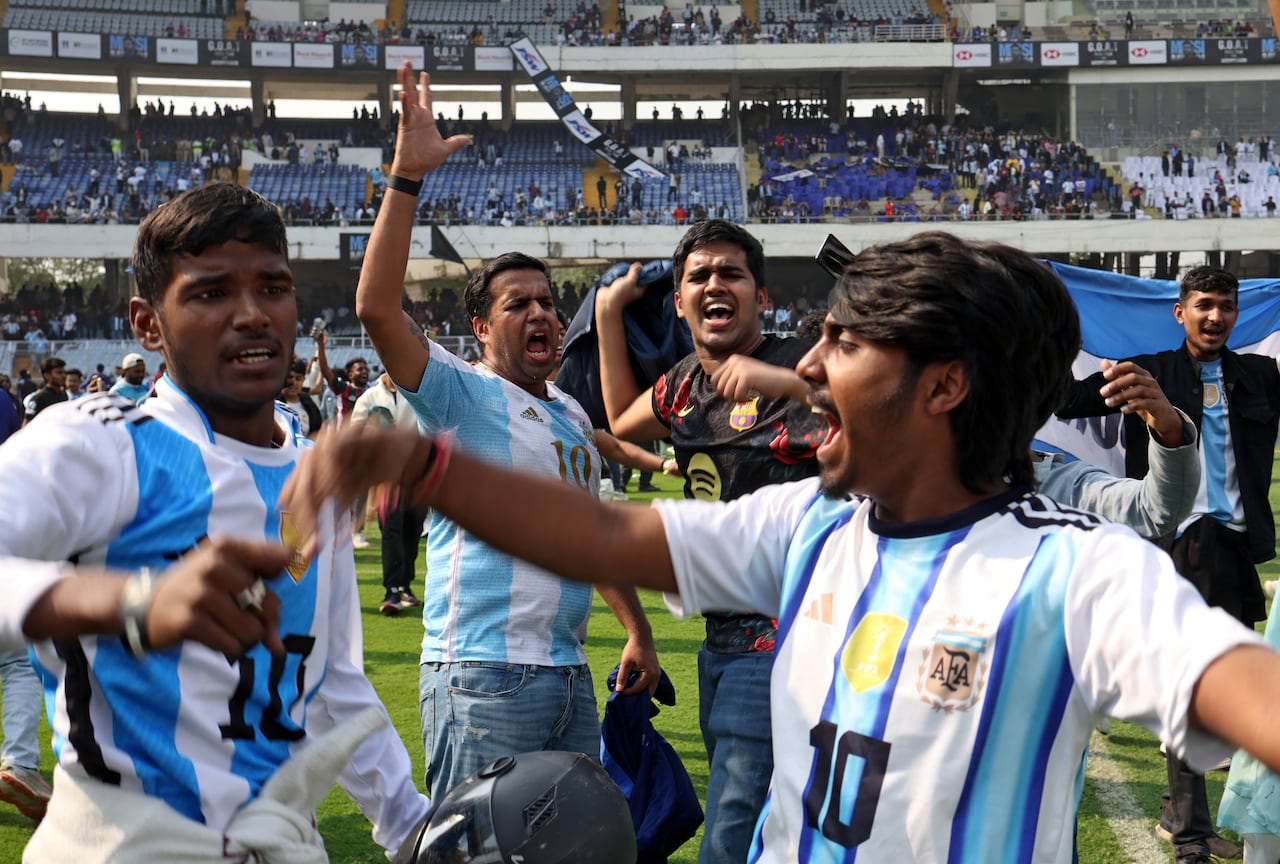 Group of men wearing Argentina jerseys stand together in a group and cheer
