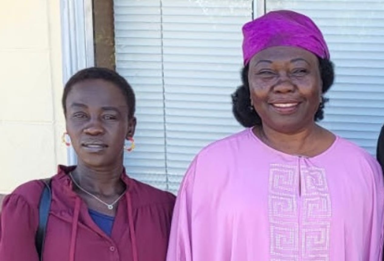 Two women stand next to each other and smile at the camera. 