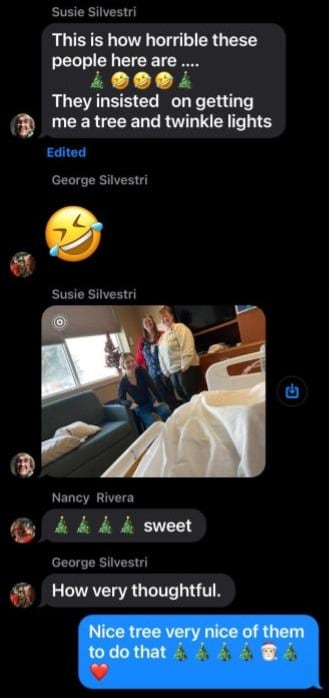 Three people pose near a small Christmas tree. 