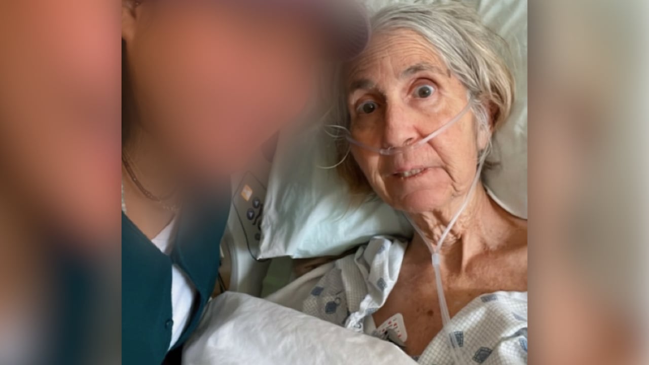 Elderly woman and a care giver posing in a hospital room. 