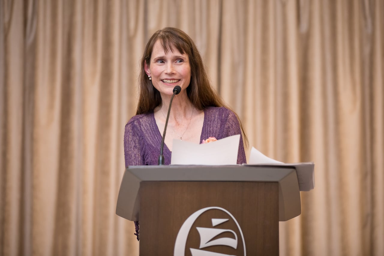 A woman reads from some papers at a podium.
