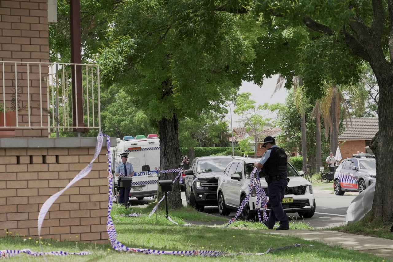 Uniformed police remove tape from outside a house.